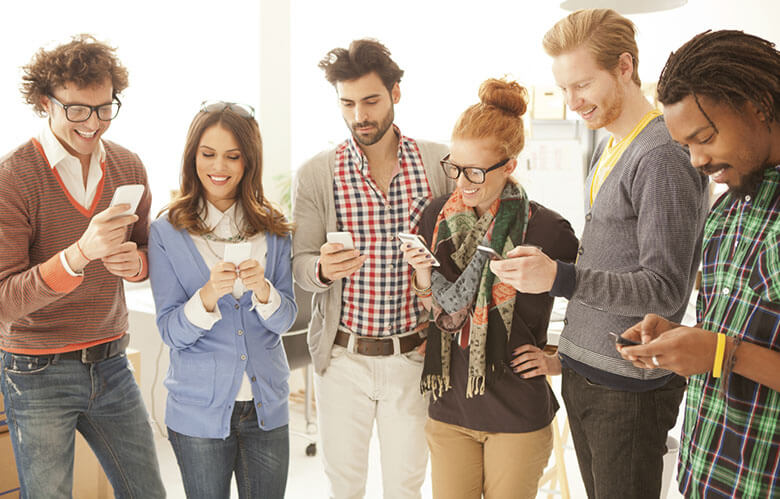 People standing next to each other looking at cell phones