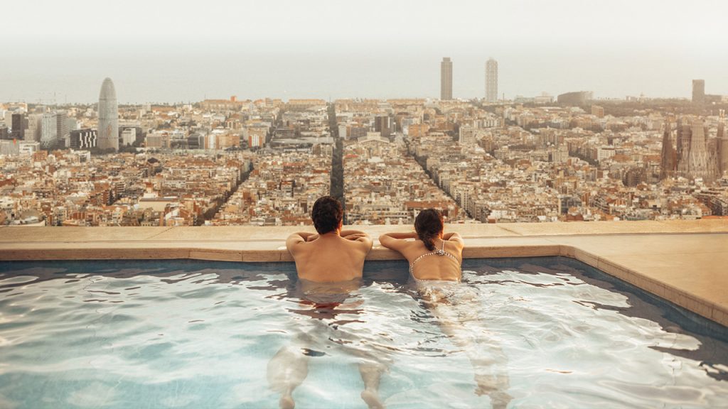 a couple enjoy the view from a rooftop pool