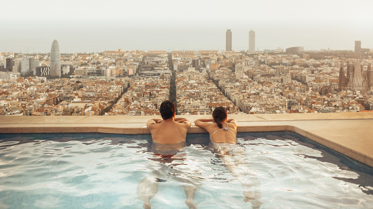 a couple enjoy the view from a rooftop pool