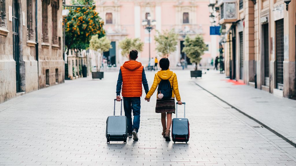 a traveling couple walks hand in hand