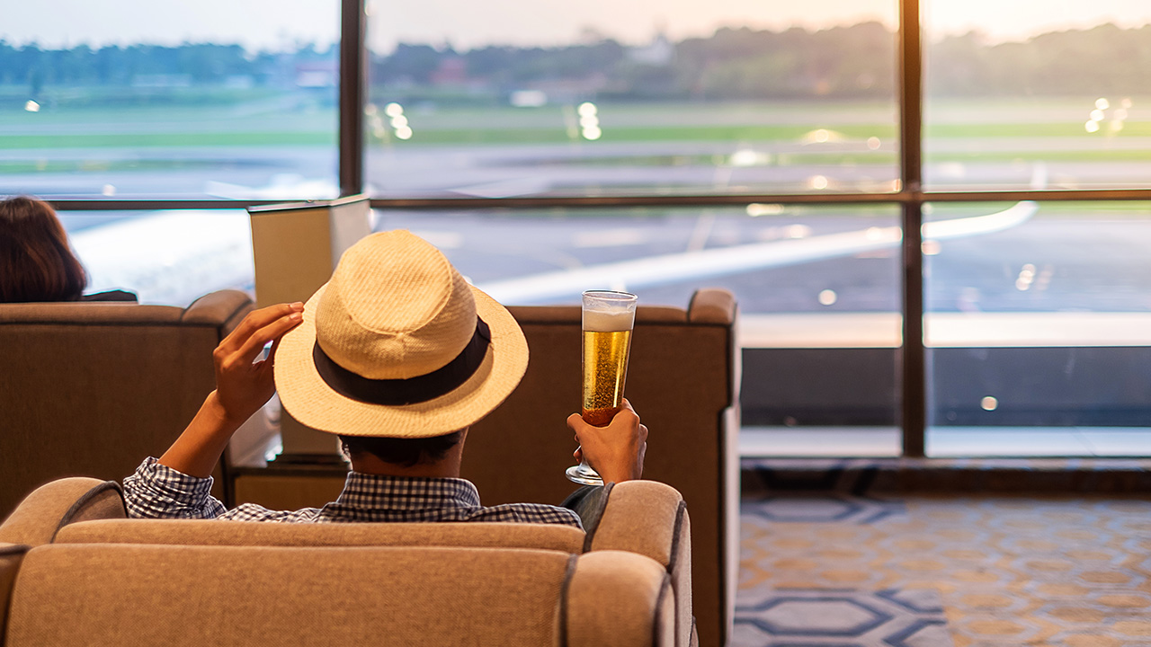Traveler has a beer in an airport lounge