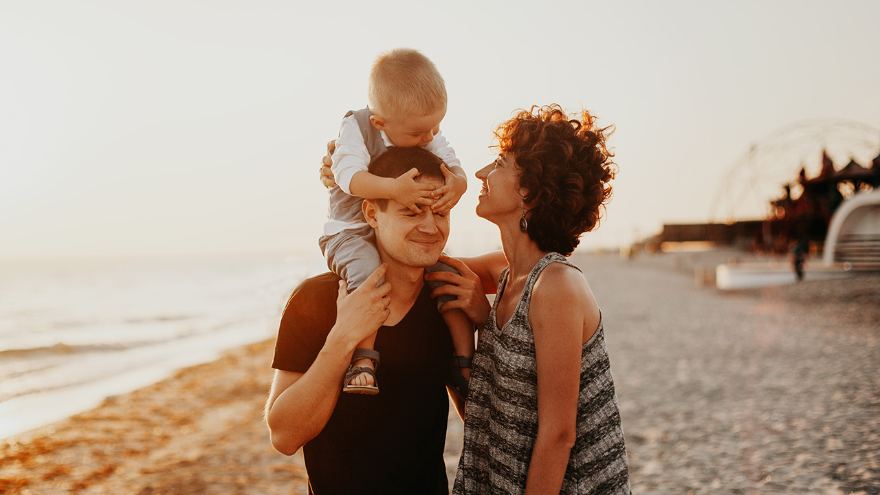 family walks along the beach at sunset