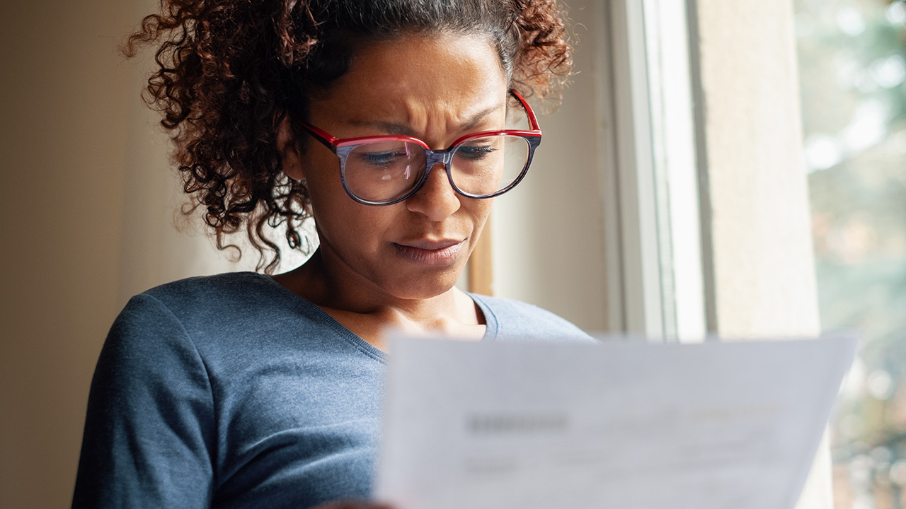 a woman looks at a letter with concern