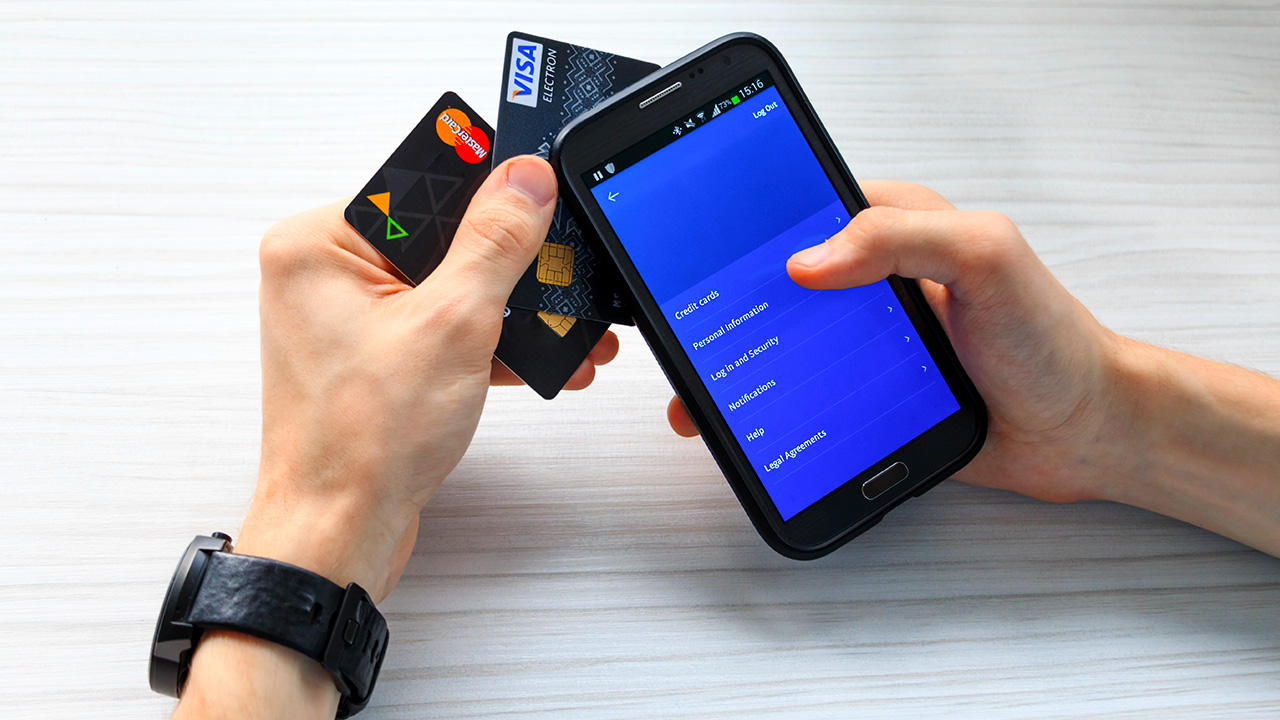 a man holds credit cards and a smartphone