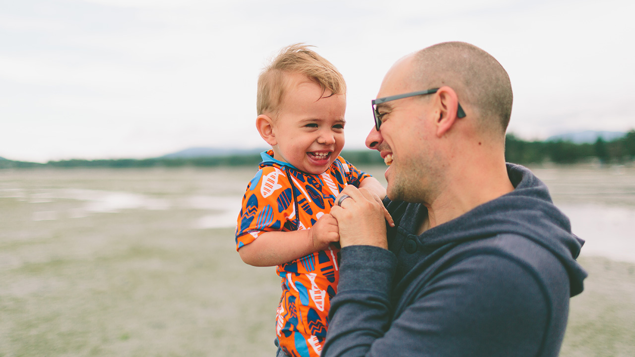 father and son laugh and hug on the beach