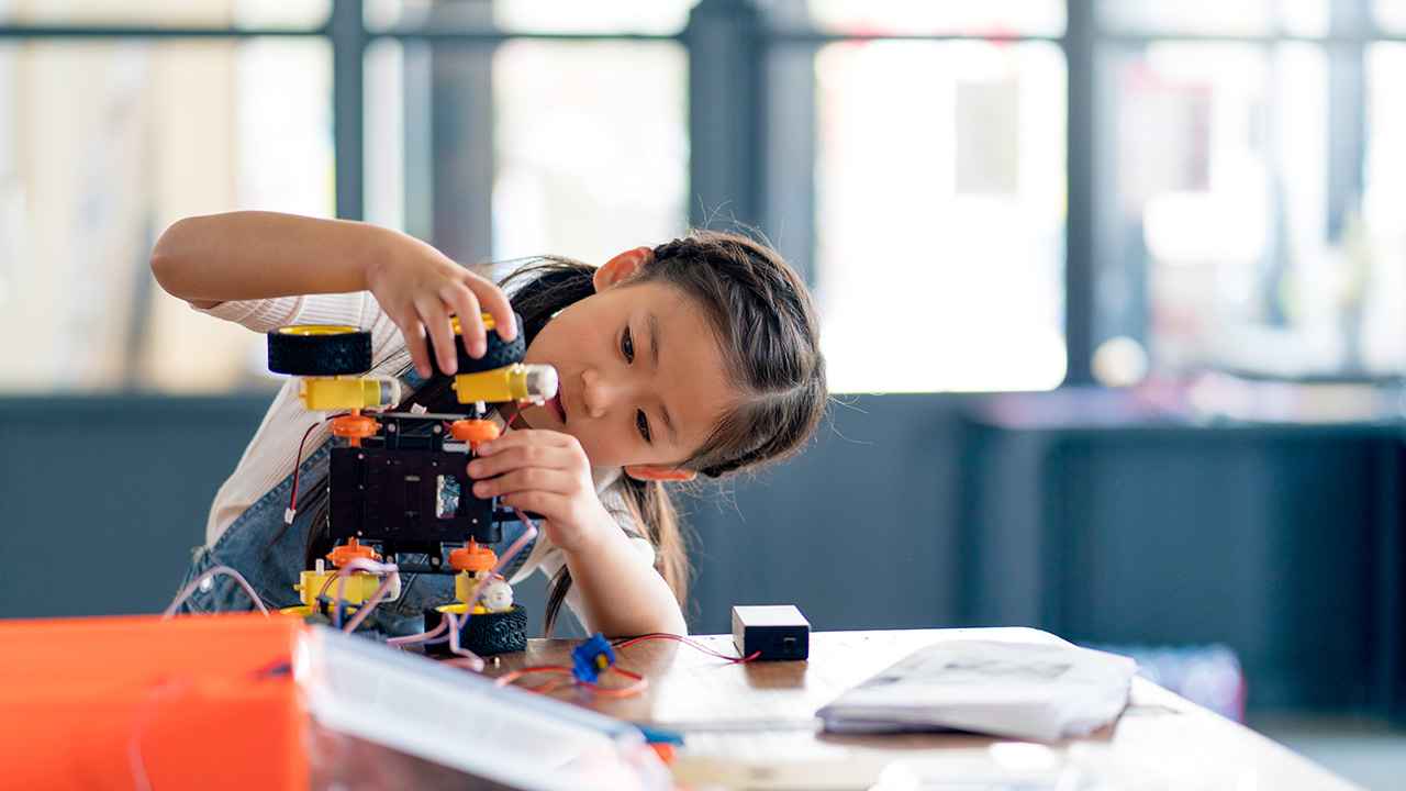 a girl builds a toy on a table