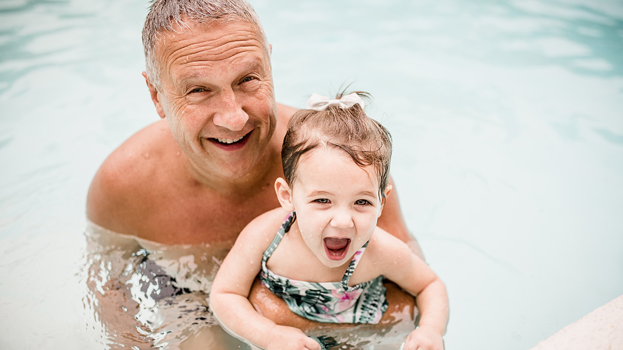 grandpa and granddaughter swim in the pool
