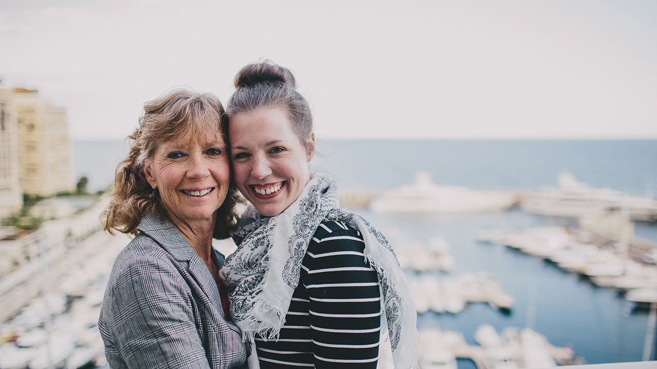 mother and daughter pose in front of a scenic view