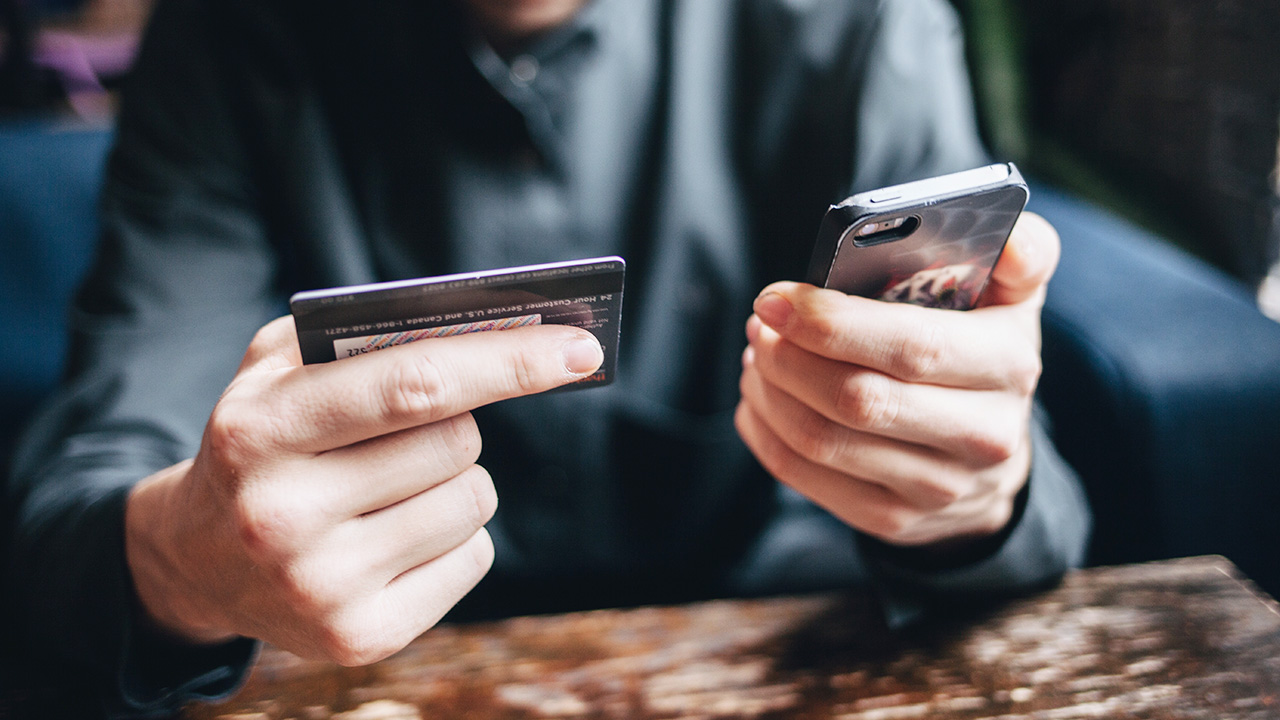 man looking at his credit card and phone