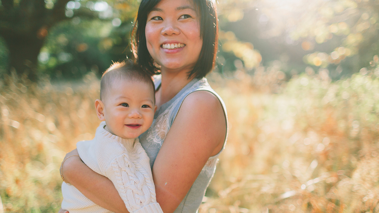Smiling mother holds child in field