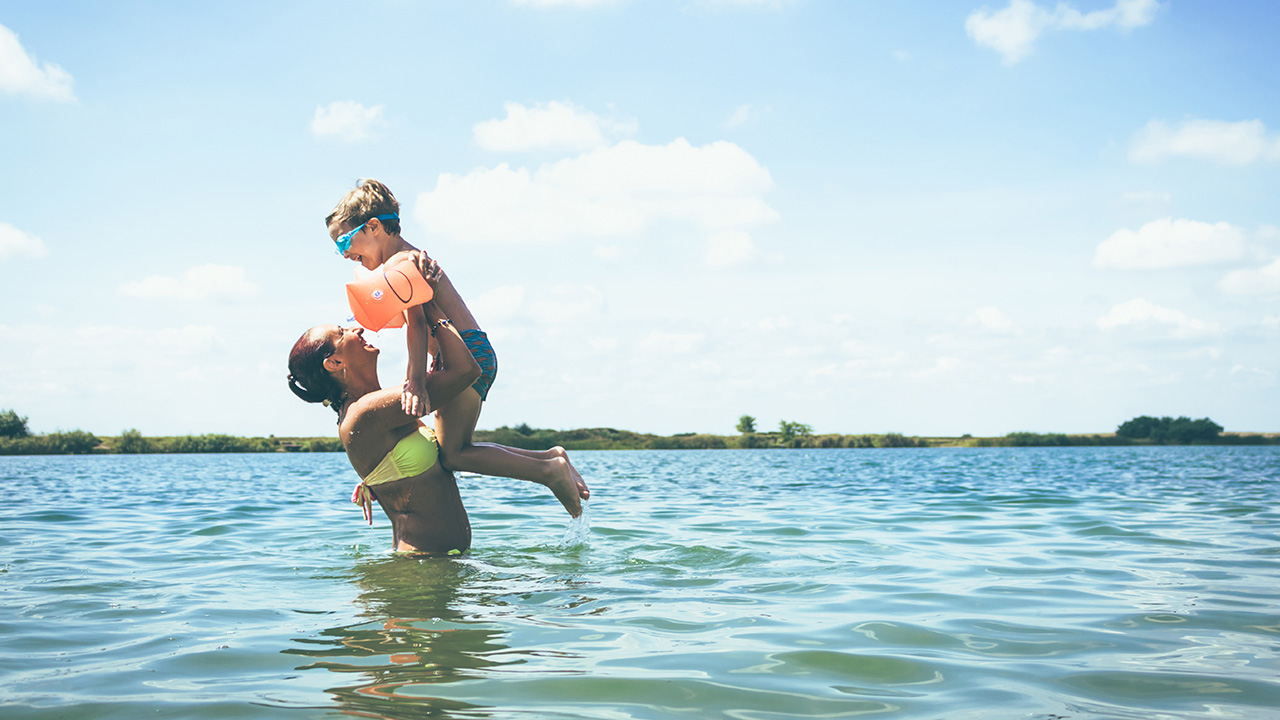 A happy mother plays with her son in the ocean