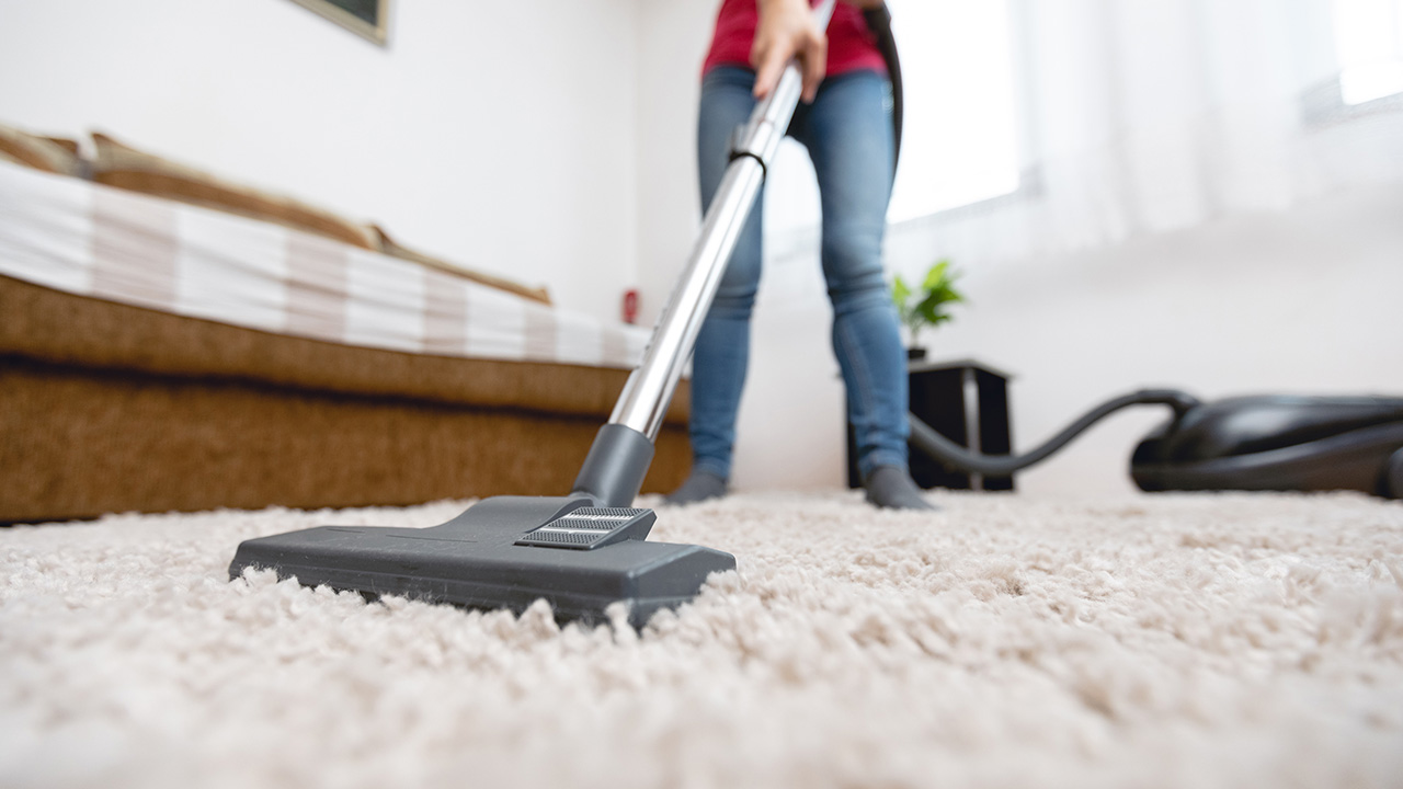 a woman vacuums the carpet