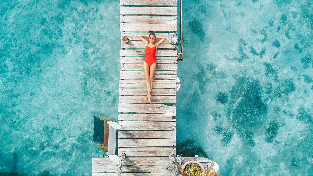 a woman sun bathes on an ocean dock