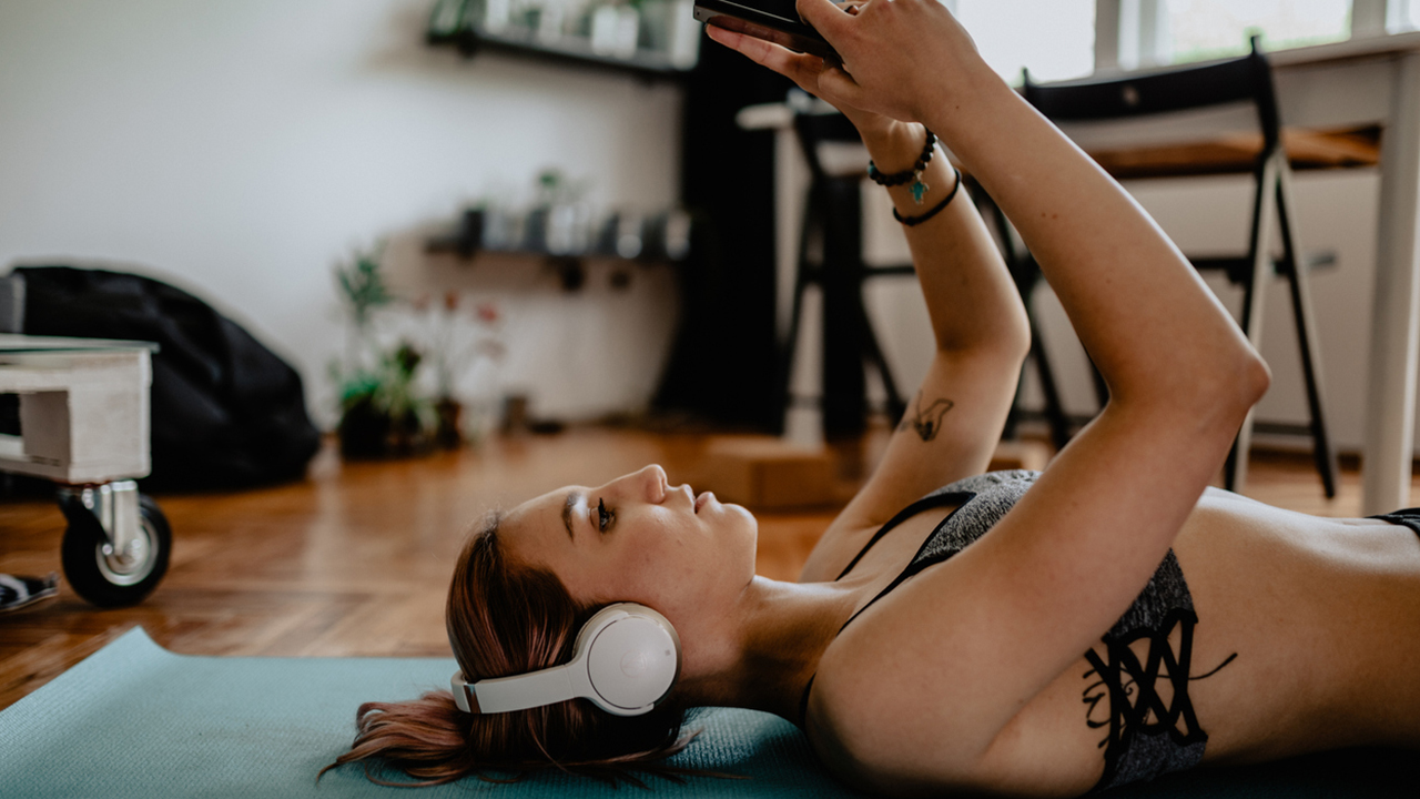 woman-doing-yoga-and-using-smart-phone-at-home
