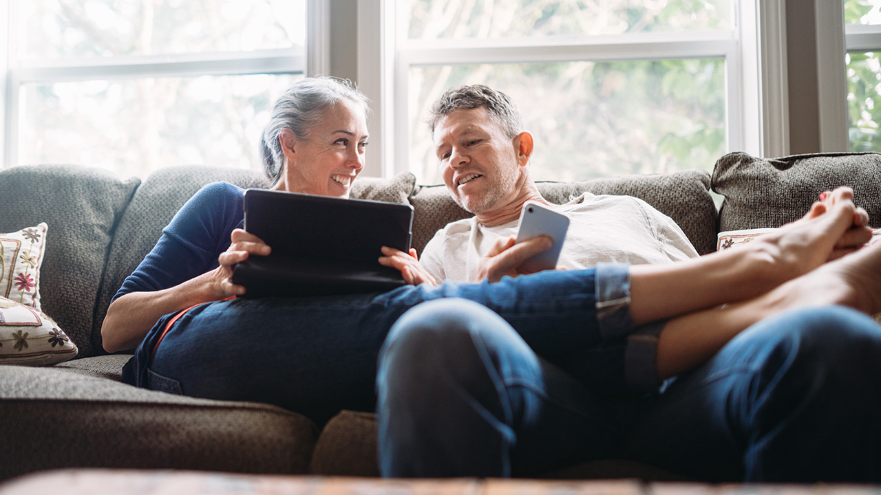 people sitting in the living room and looking at a tablet