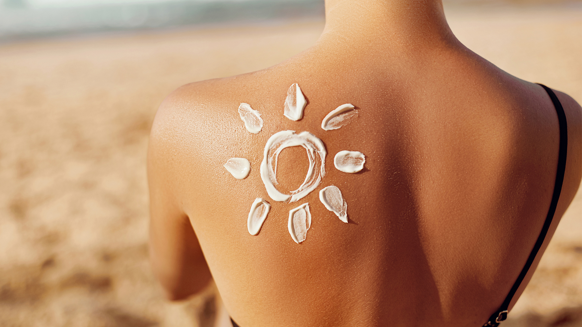 iStock hero-woman wearing sunscreen on beach in shape of sun