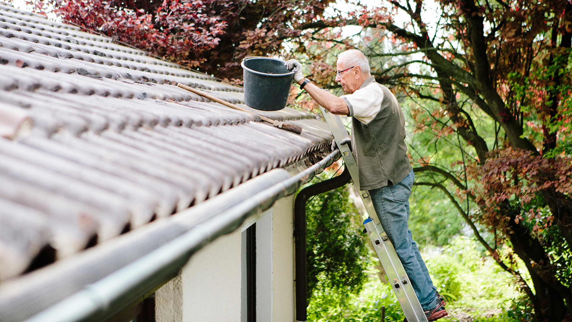 iStock-965015416 fotografixx hero man cleaning gutters home roof