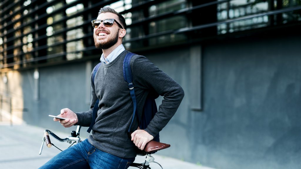 man on bike smiling holding phone hero