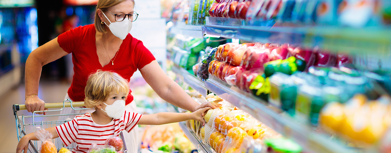 woman and child shopping for groceries wearing face masks