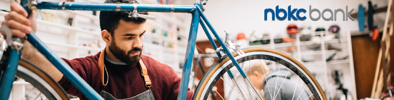 Bike shop owner working on vintage bicycle with NBKC logo