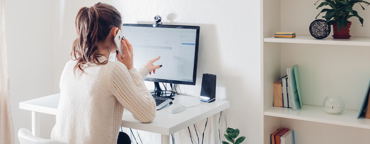 Woman stays home talking on phone. Workspace of freelancer. Office interior with computer