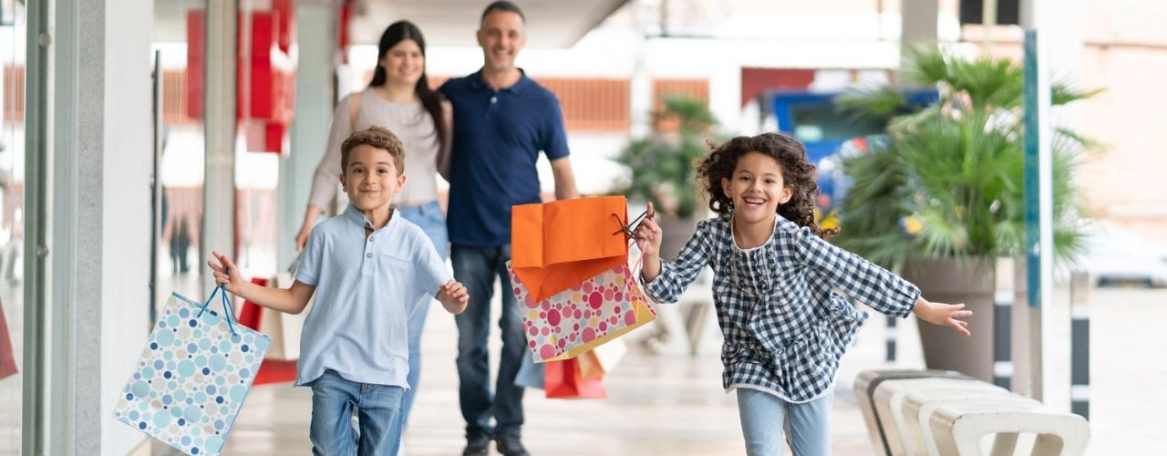 siblings having fun at the mall running and holding shopping bags