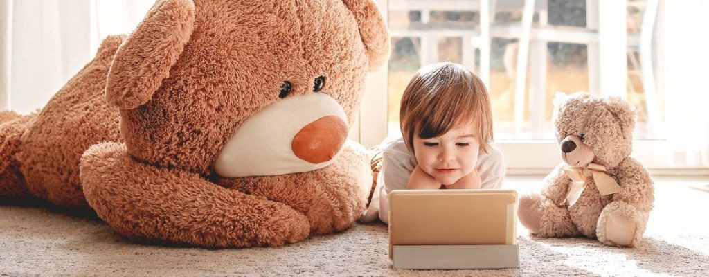 child watching cartoons on digital tablet device lying on floor