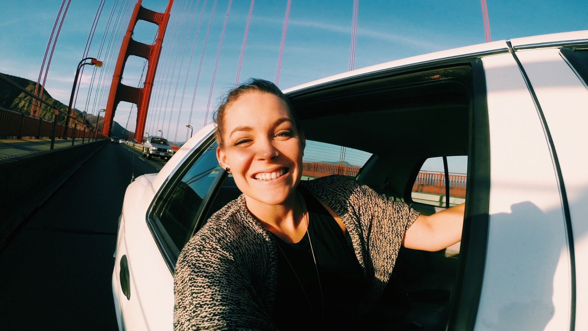 Woman smiling enjoying a drive in San Francisco on a sunny day looking out the window
