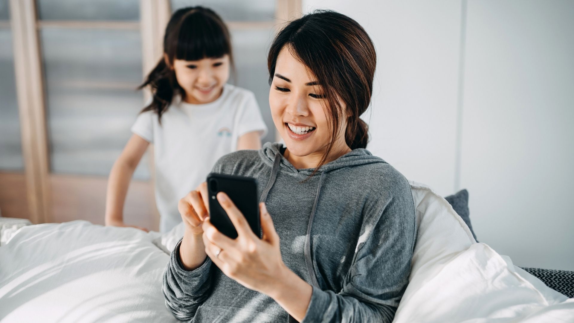 mom on her smartphone with daughter behind her
