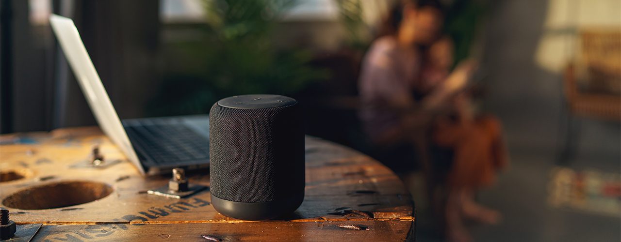 bluetooth speaker and laptop on tabletop at sunset