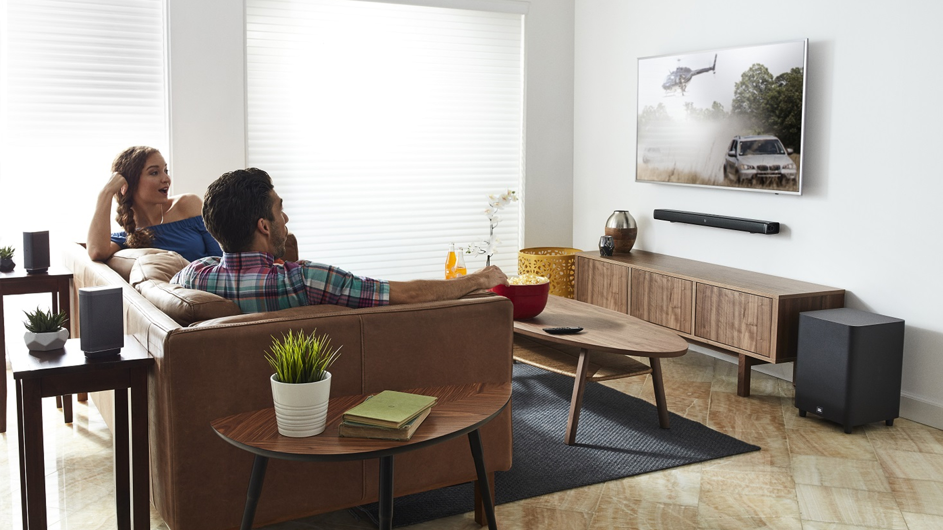 man and woman watching movie with JBLBAR51BLKAM jbl speakers surround sound in home white walls hero