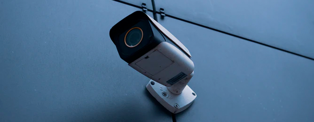 security camera on side of building with blue metal siding grey sky