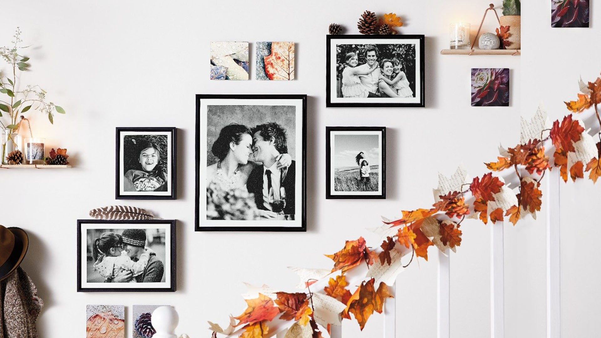 Framed family photos hanging on a wall with fall decorations.