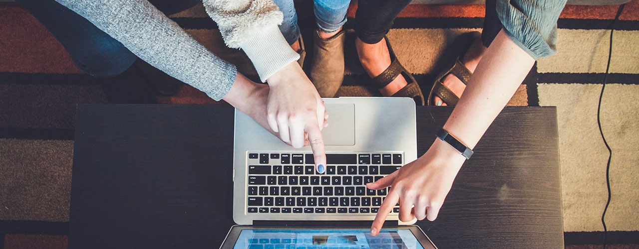 people pointing at laptop computer screen