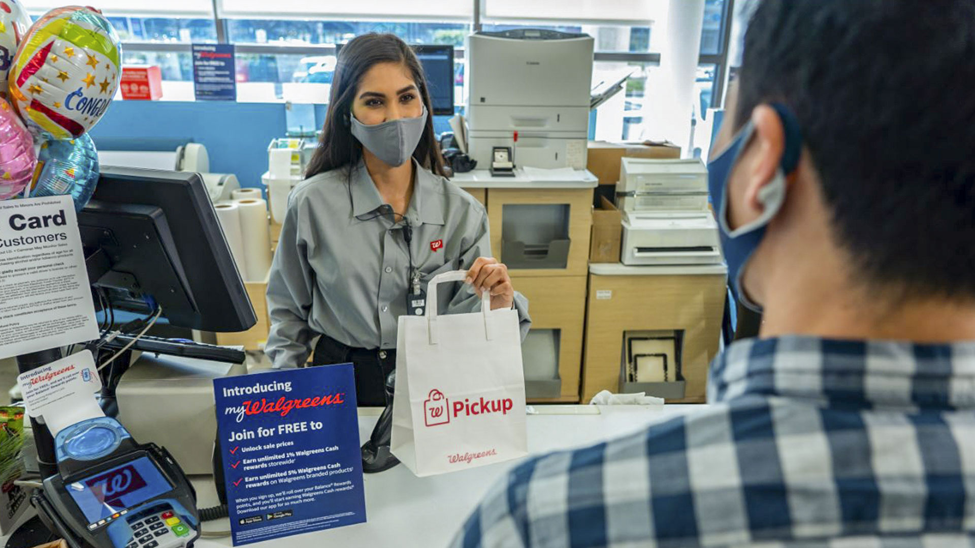 walgreens employee handing pickup bag to customer
